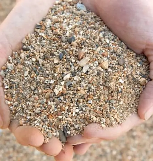 An image of two hands holding a considerable amount of coarse sand.